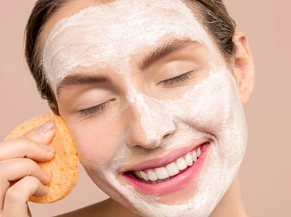 woman-smiling-while-cleaning-her-face